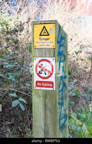 Avertissement sur wooden post : Danger câbles électriques aériens, aucune pêche Banque D'Images