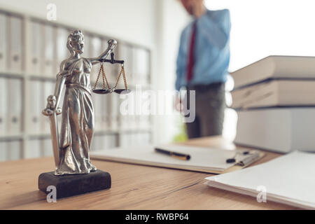 Procureur talking on mobile device dans law office, selective focus on statue de Dame Justice Banque D'Images