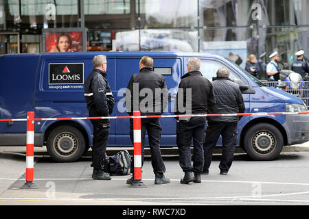 06 mars 2019, en Rhénanie du Nord-Westphalie, Köln : policiers et la sécurité des employés d'une entreprise sont debout à une voiture blindée. Au moins un coup de feu a été tiré le mercredi au cours d'un vol d'un transporteur d'argent à l'aéroport Cologne/Bonn. Photo : Oliver Berg/dpa Banque D'Images