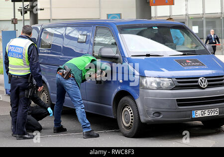 06 mars 2019, Berlin, Cologne : les enquêteurs de police sont la sécurisation des pistes sur une voiture blindée. Au moins un coup de feu a été tiré le mercredi au cours d'un vol d'un transporteur d'argent à l'aéroport Cologne/Bonn. Photo : Oliver Berg/dpa Banque D'Images