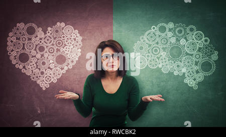 Femme perplexe sur split tableau noir avec cœur et cerveau symbole sur différents côtés. Décision difficile, choix entre le cœur et l'esprit. Les droits de l'charact Banque D'Images