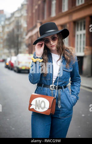 LONDON - 15 février 2019 : les participants à l'extérieur rassemblement élégant 180 The Strand pour la Semaine de la mode de Londres. fille en bleu denim jumpsuit large-débordé et h Banque D'Images