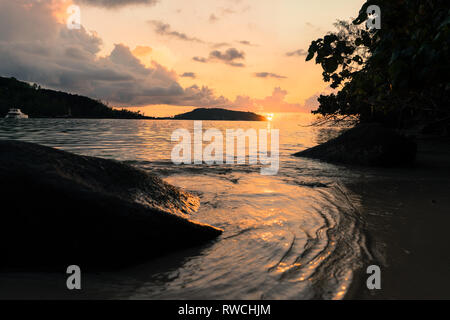 Coucher de soleil sur une plage de la baie de l'île de Mahé, Seychelles Banque D'Images