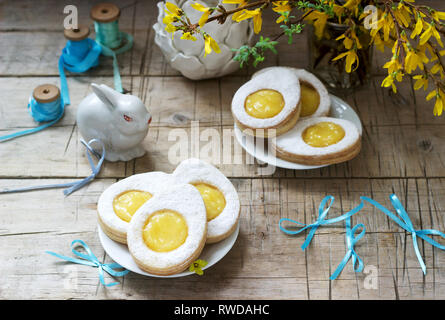 Composition de Pâques avec des cookies en forme d'œuf rempli de lait caillé de citron, lapin, bouquet de forsythia et d'arcs. Focus sélectif. Banque D'Images