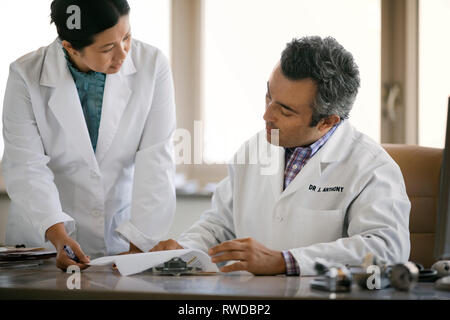 Young doctor consulting avec un ancien superviseur à leur pratique. Banque D'Images