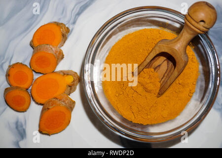 Poudre de curcuma dans la cuillère en bois et bol en verre et le curcuma frais racine. Banque D'Images