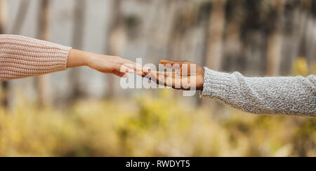 Multi-ethnic couple mains tendues et touchant à l'extérieur. Approche de couple à l'autre. Les hommes et les mains qui se touchent par les doigts. Banque D'Images