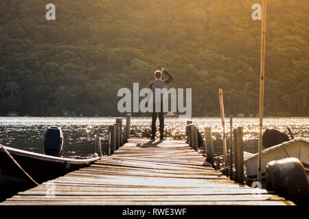 Vie paisible coup de jeune homme au bord d'un quai - coucher de soleil à Florianópolis - Santa Catarina - Brésil Banque D'Images