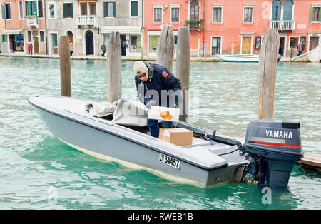 Un homme d'essayer de lancer un bateau à moteur dans une jetée sur Murano Banque D'Images