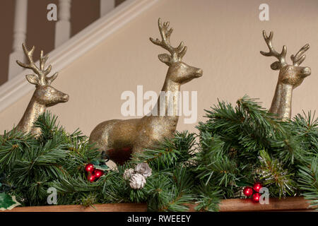 Trois décorations de Noël renne d'or sur un manteau d'avec green garland Banque D'Images