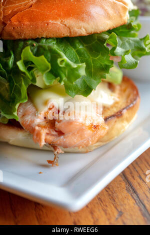 Saumon grillé sur un petit pain grillé avec laitue et fromage, servi avec un petit bol de salade de choux Banque D'Images