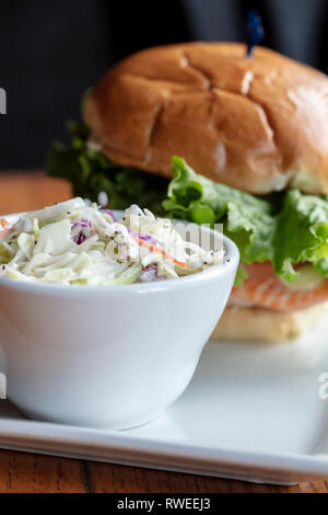 Saumon grillé sur un petit pain grillé avec laitue et fromage, servi avec un petit bol de salade de choux Banque D'Images