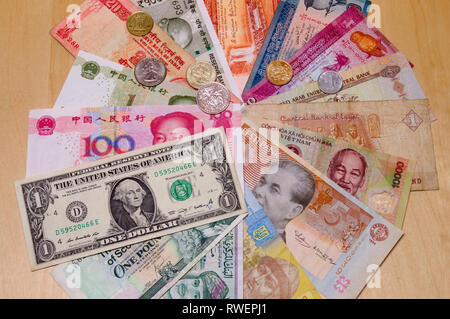 Divers billets de différents pays disposés sur table avec quelques pièces sur le dessus - monnaie, argent, billets, monnaies, argent comptant Banque D'Images