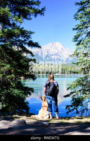 Une femme et son Golden Retriever s'interrompe tout en faisant de la randonnée autour du lac Beauvert dans le parc national Jasper, à Jasper, en Alberta, le mont Pyramid est en arrière-plan Banque D'Images