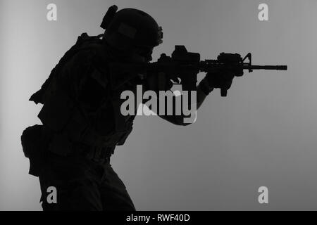 Silhouette d'un Corps des Marines américains Marsoc raider visant gun, fond gris. Banque D'Images