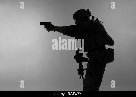 Silhouette d'un Corps des Marines américains Marsoc raider visant pistolet, fond gris. Banque D'Images