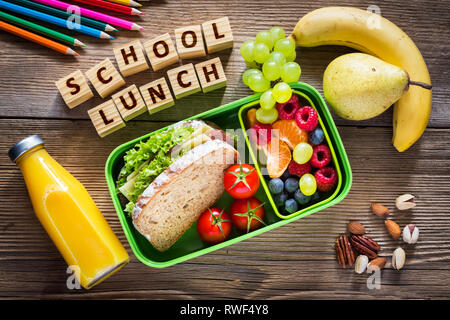 De saines habitudes alimentaires concept. Déjeuner à l'école fort avec sandwich, fruits, légumes, jus d'orange et les noix. Banque D'Images