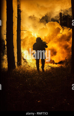 Silhouette en contre-jour des forces spéciales de l'opérateur maritime en forêt avec explosion de feu en arrière-plan. Banque D'Images