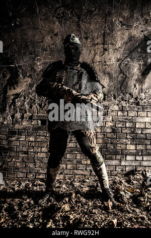 Soldat post apocalyptique avec des armes à feu à la main et l'armure de corps dans un bunker abanonded. Banque D'Images