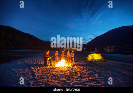 Groupe d'amis autour de feux de camp en soirée à la plage de troupe à Nelson en Colombie-Britannique Banque D'Images