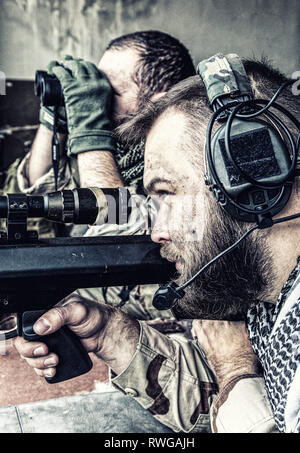 Joint Marine de l'équipe de tireurs d'engager des objectifs d'un bâtiment en ruine avec un fusil de sniper. Banque D'Images