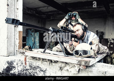 Joint Marine de l'équipe de tireurs d'engager des objectifs d'un bâtiment en ruine avec un fusil de sniper. Banque D'Images