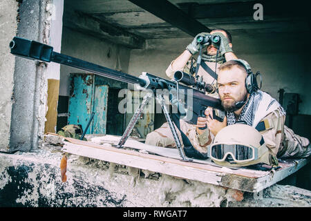 Joint Marine de l'équipe de tireurs d'engager des objectifs d'un bâtiment en ruine avec un fusil de sniper. Banque D'Images