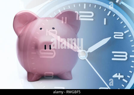 Pink piggy bank recouvrement sur un cadran d'horloge bleu avec les heures et les minutes du temps qui passe conceptuel, un délai de paiement ou compte à rebours Banque D'Images