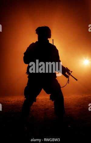 Silhouette de soldat d'infanterie moderne debout avec fusil d'assaut sur fond de couleur. Banque D'Images