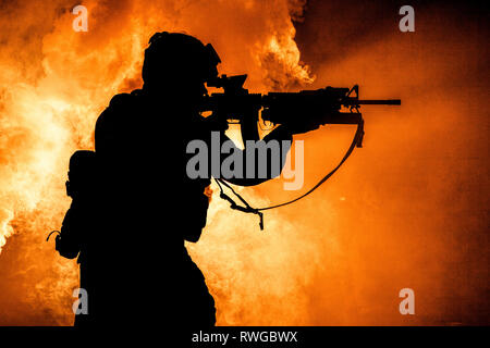 Silhouette de soldat d'infanterie moderne debout avec fusil d'assaut sur fond de couleur. Banque D'Images