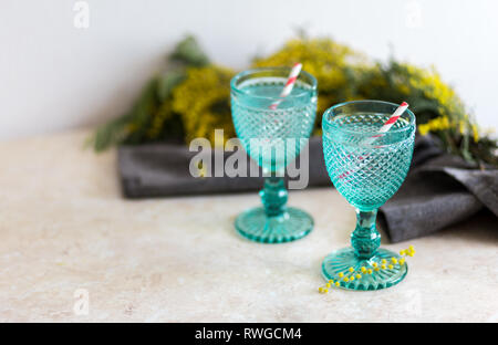 Refhesing boire dans des gobelets vintage bleu sur le fond blanc avec fleurs srping. Mimosa Banque D'Images