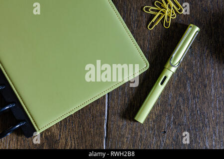 Close up étudier une collection de papeterie en lime green - l'ordinateur portable, stylo et les trombones sur un bureau en bois vintage Banque D'Images