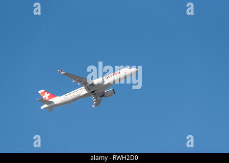 Avion à réaction suisse Airbus A220 HB-JCO décollant de l'aéroport de Londres Heathrow, Royaume-Uni, dans un ciel bleu. Swiss International Air Lines Banque D'Images