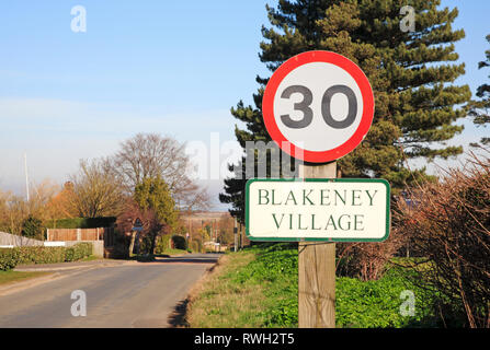 Un signe de 30 mi/h et sur le nom de village Langham Road entrant dans le village de North Norfolk Blakeney, Norfolk, Angleterre, Royaume-Uni, Europe. Banque D'Images
