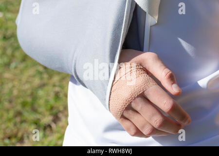 Un garçon avec une main blessée dans un bandage de fixation sur l'arrière-plan d'un terrain de football, des prés Banque D'Images