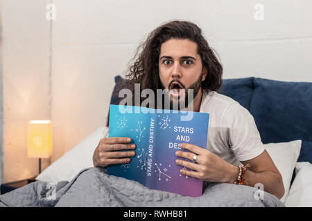 L'homme excité agréable de lire un livre intéressant Banque D'Images