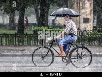 La Havane, Cuba. 29 mai, 2009. Un homme chevauche son vélo à la rue pendant un orage à La Havane, Cuba. Crédit David Creedon / Alamy Banque D'Images