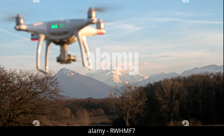 D'un drone en vol stationnaire devant un fond coucher de soleil. Le drone est immobile planant au-dessus du sol que les couchers de soleil au loin. Banque D'Images