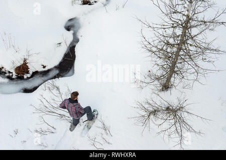 L'homme seul en raquettes le long d'un ruisseau en hiver. Mont Tremblant, Québec, Canada Banque D'Images