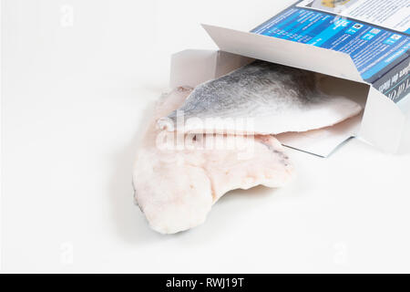 Du poisson congelé dans une boîte en carton sur une surface blanche Banque D'Images