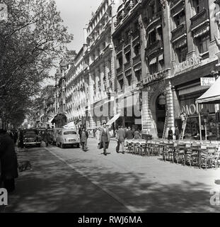 1950s, Paris, France, une petite rue à côté de l'avenue des champs Elysées avec des bureaux, des boutiques et des cafés au niveau de la rue et des voitures de l'époque garées. Banque D'Images