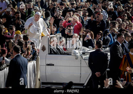 Pape Francis vu rouler sur le pape-mobile à travers la foule des fidèles comme il arrive à diriger l'audience générale hebdomadaire à la place Saint Pierre. L'Audience générale a lieu tous les mercredi, quand le Pape est dans la Cité du Vatican à la place Saint Pierre, qui peut accueillir environ 80 000 personnes. Au cours de l'Audience générale, également appelé l'Audience Papale, le Saint Père s'adresse à la foule dans différentes langues. Banque D'Images