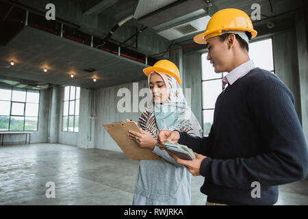 Deux ingénieur avec l'équipement de sécurité dans le hall espace projet de construction Banque D'Images