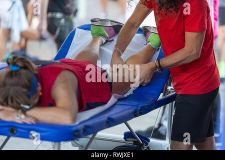 Étendu sur un lit de l'athlète tout en ayant les jambes massées après un entraînement physiques sportives. Banque D'Images