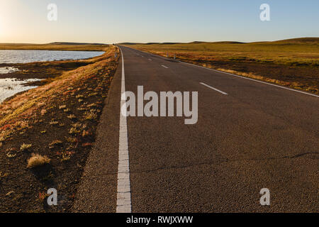 Route asphaltée en steppe mongole le long d'un petit lac, la Mongolie Banque D'Images