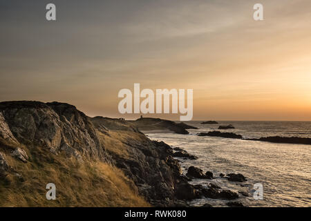 Vue côtière d'un coucher de soleil d'hiver, à la péninsule dans la lumière du soir, à l'île Llanddwyn, Anglesey, au nord du Pays de Galles. Banque D'Images