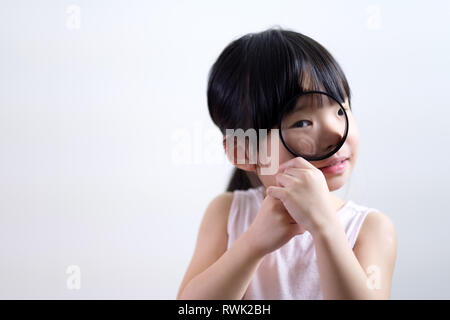 Peu de petites filles à travers une loupe sur fond blanc Banque D'Images