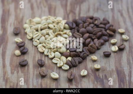 Un coeur formé de deux moitiés, l'une est faite avec des grains de café et l'autre moitié est composée de grains de café torréfiés, sur une table en bois vintage Banque D'Images