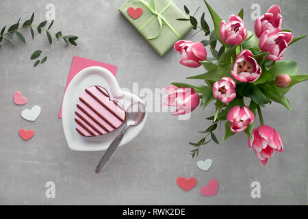 Coeur rose glace sur une plaque en céramique et bouquet de tulipes roses, Saint Valentin ou anniversaire télévision jeter sur fond de pierre Banque D'Images