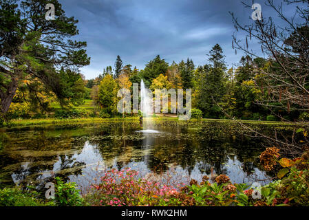 Une fontaine dans un bassin entouré de plantes et d'arbres en fleurs, Powerscourt Estate, Enniskerry, comté de Wicklow, Irlande Banque D'Images
